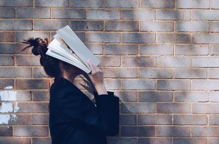 Stressed woman put her face in a book