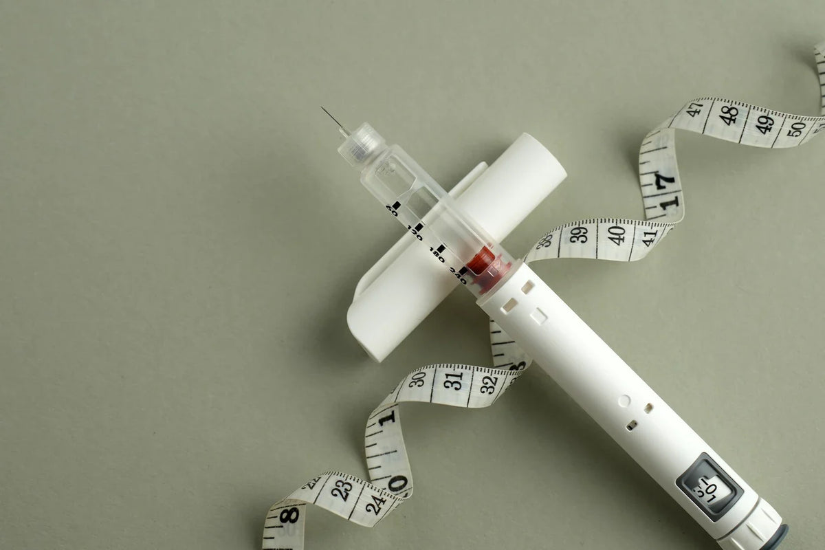 A close-up of a GLP-1 injector with tailor’s measuring tape spiraling behind it.