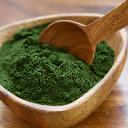 A spoon scooping up Sun Chlorella Powder from a bowl