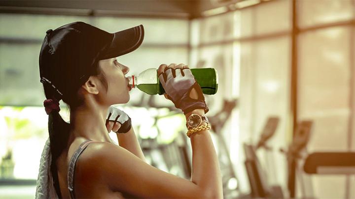 a woman drinking a green chlorella drink after a work out