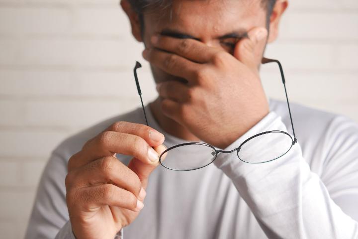 Man taking off glasses tiredly