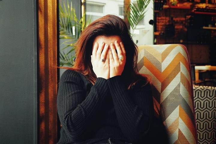 Stressed woman placing her face in hands