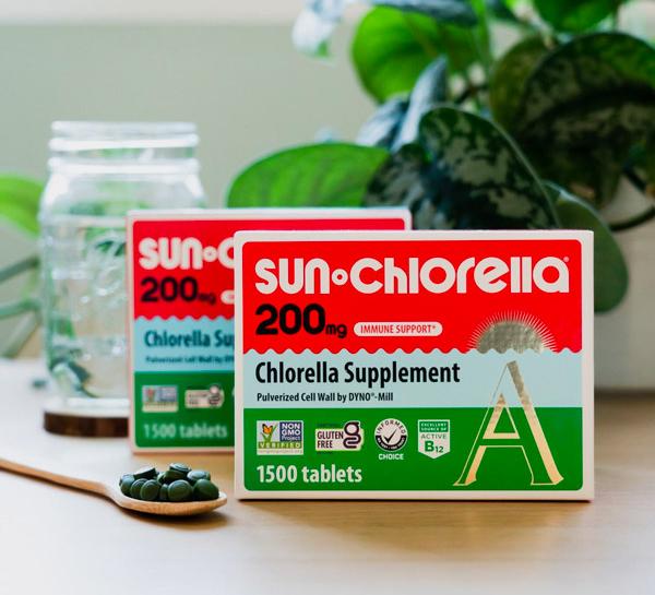 2 boxes of 1500 Sun Chlorella 200mg tablets family size on the table with a spoon filled with Sun Chlorella tablets