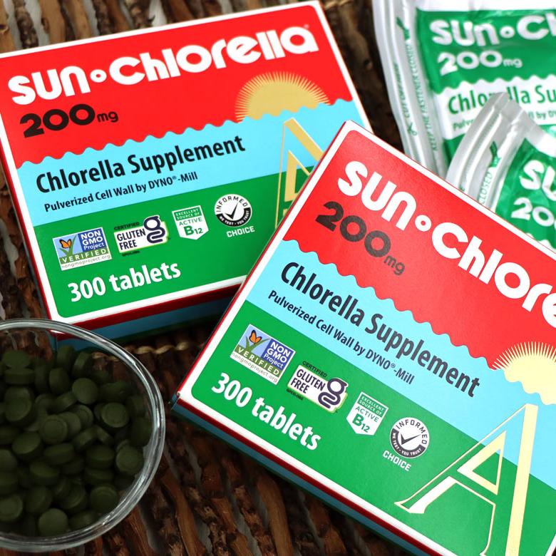 2 boxes of Sun Chlorella 200mg tablets (300 tablets each) next to a small glass bowl filled with the 200mg chlorella tablets.