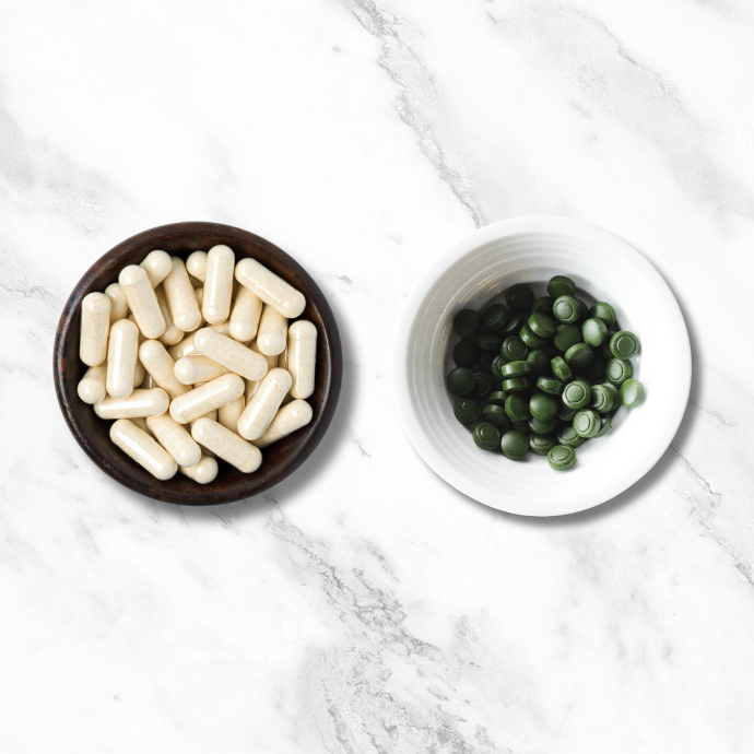Bowl of Sun Neuro capsules next to a bowl of Sun Chlorella tablets