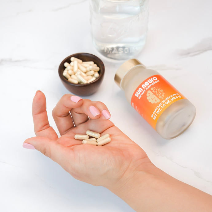 Hand holding multiple Sun Neuro memory supplement pills
