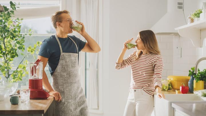 Couple drinking a smoothie after cooking 