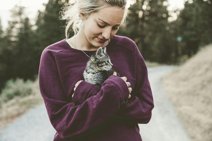 Caring woman holding her pet cat outside